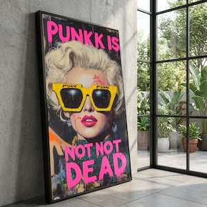 May include: A framed art print featuring a portrait of a woman with blonde hair and bright pink lipstick, wearing yellow sunglasses with the word "PUNK" on them. The words "PUNK IS NOT NOT DEAD" are written in pink. The artwork has a grunge aesthetic.
