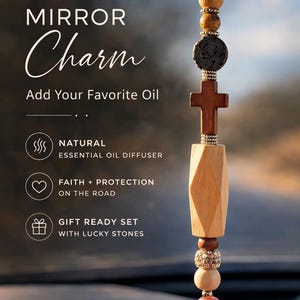 May include: A car rear view mirror charm featuring a wooden cross and assorted beads. The charm is designed for essential oils, with a faceted wooden element and a pink stone. The image text reads "Add Your Favorite Oil".