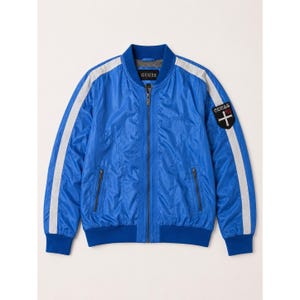 May include: A bright blue bomber jacket featuring a full-length front zipper, ribbed collar, cuffs, and hem. The sleeves have white vertical stripes, and a black shield-shaped patch on the left sleeve displays the text GUESS 81 with a cross.