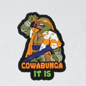 May include: A patch featuring a cartoon turtle in an orange Hawaiian shirt, eating pizza. The patch has the words "COWABUNGA IT IS" in orange and green. The turtle is holding a blue weapon.