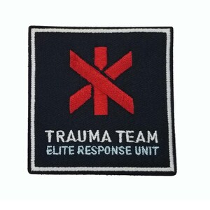 May include: A square embroidered patch with a black background and a white border. Centered is a red Star of Life symbol. Below the symbol, the white text reads TRAUMA TEAM and ELITE RESPONSE UNIT in two lines, featuring a clean, bold font style.