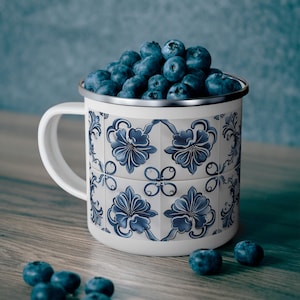 May include: A white ceramic mug with a black handle and the text "But First, Coffee" in a black, bold font. The mug is on a white surface. The mug is approximately 10 cm tall.