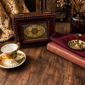 May include: A rectangular dark brown wooden box with a central decorative panel featuring a black star and crescent moon design. The box is accented with small metal studs along the edges and includes a gold-toned metal hinge on the top lid.