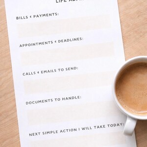 Puede incluir: Un papel blanco titulado "LIFE ADMIN RESET" con secciones para facturas, citas, llamadas, documentos y una acción diaria. Una taza blanca llena de café está a la derecha. El texto "CLEAR ADMIN. CLEAR MIND." está en la parte inferior.