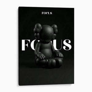 May include: A matte black figurine with rounded ears and X-shaped eyes sits in a cross-legged position against a dark background. The word FOCUS is printed in white text above the figure and in large white letters behind the figure.