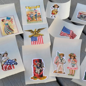 May include: A selection of small, off-white paper bags adorned with vintage-style patriotic stickers. The stickers depict the American flag, children, eagles, and other patriotic symbols. The bags are arranged on a weathered wooden surface.