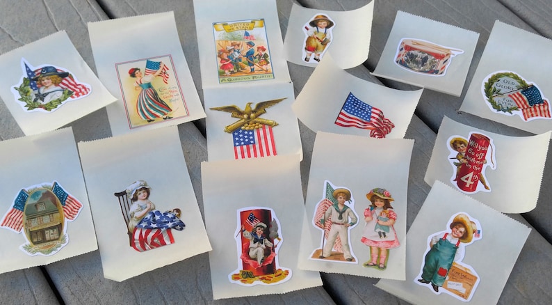 May include: A selection of small, off-white paper bags adorned with vintage-style patriotic stickers. The stickers depict the American flag, children, eagles, and other patriotic symbols. The bags are arranged on a weathered wooden surface.