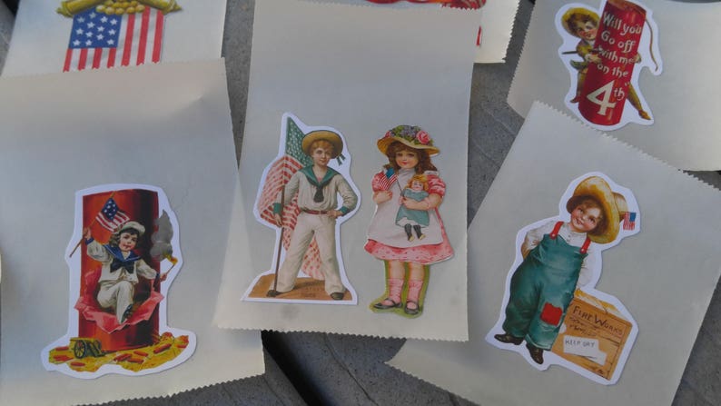 May include: Paper bags decorated with vintage stickers. The stickers depict children in patriotic attire, including sailor suits and overalls, holding flags and dolls, and a firework display with the text "4th".