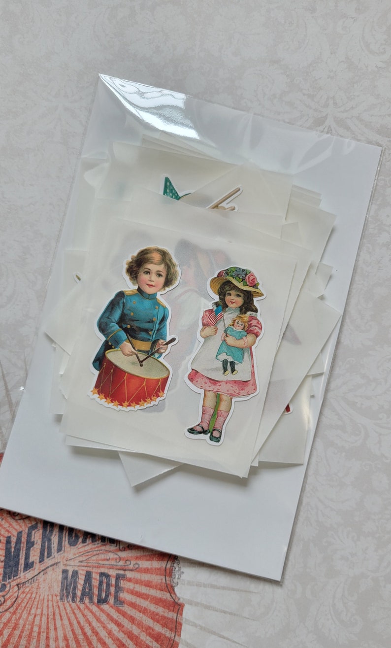 May include: A selection of vintage-style stickers featuring children. One sticker shows a boy in a blue uniform playing a red drum. Another depicts a girl holding a doll and a small American flag. The stickers are packaged in a clear plastic bag.