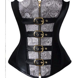 May include: Black and silver steampunk corset with a paisley pattern on the front panel. The corset features a gold zipper, black leather trim, and decorative buckles. The garment is designed for a vintage aesthetic.