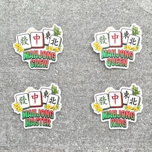 May include: Four stickers with a Mahjong theme. Each sticker features three Mahjong tiles, yellow flowers, and bamboo. The stickers have the words "Mahjong Crew", "Mahjong Queen", "Mahjong Master", and "Mahjong King".