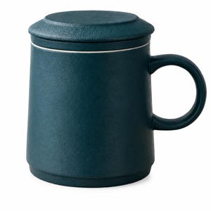 May include: A dark teal ceramic mug with a matching lid and a curved handle. The mug features a textured, matte finish and a subtle white rim detail where the lid meets the body. The design is cylindrical with a slightly wider base.