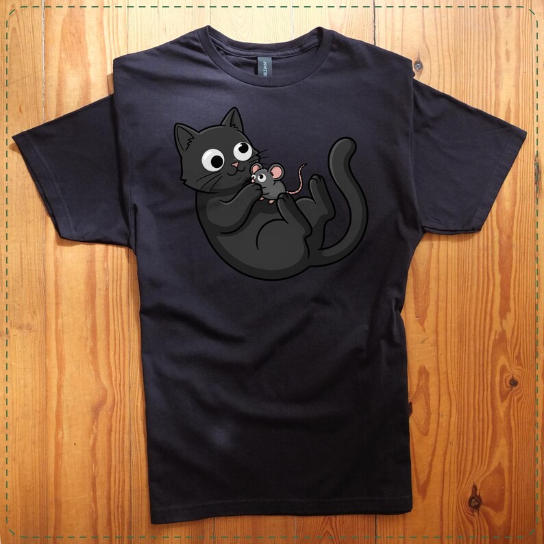 May include: Black t-shirt featuring a cartoon cat holding a mouse. The cat is black with large white eyes and a playful expression. The mouse is gray with pink ears and a long tail. The design is centered on the shirt.