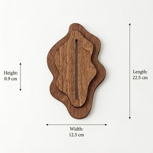 May include: A layered wooden display stand with an irregular, organic shape and a central vertical slot. The object measures 22.5 cm in length, 12.5 cm in width, and 0.9 cm in height, as indicated by the text labels and arrows in the image.