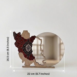 May include: A wooden decorative object featuring a circular mirror attached to a cutout shape with a red and black intricate patterned overlay. The item measures 16.5 cm (6.5 inches) in height and 22 cm (8.7 inches) in width as indicated by labels.