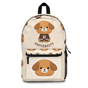 Puede incluir: Mochila beige con un perro de dibujos animados que lleva un suéter marrón con una "U". La mochila tiene un bolsillo frontal con una cara de perro y la palabra "UNIVERSITY" debajo. Huellas de patas marrones y caras de perro decoran la bolsa.