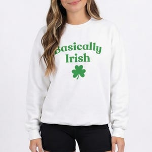 Könnte beinhalten: Weißes Sweatshirt mit Rundhalsausschnitt und dem grünen Schriftzug „Basically Irish“ sowie einer grünen Kleeblatt-Grafik. Das Sweatshirt ist ein lässiger Stil, passend für St. Patrick's Day oder den Alltag.