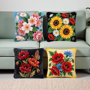 May include: Four decorative throw pillows with floral designs. One pillow features pink and white flowers on a blue background. Another has sunflowers, daisies, and red poppies on black. The third displays red poppies and a butterfly. The last has red poppies and blue cornflowers.