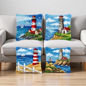 Puede incluir: Cuatro cojines decorativos con diseños de faros. Cada cojín presenta una escena costera diferente con un faro, olas del océano y cielo azul. Los cojines tienen un borde texturizado y peludo.