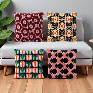 May include: Four square scatter cushions with textured punch needle embroidery. The top left features dark red flowers with pink centres. The top right has a black, orange, and cream geometric pattern. The bottom left shows tulips, and the bottom right has black and pink shapes.