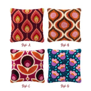 May include: Four square throw pillows with textured punch needle designs. Style A features maroon, pink, and yellow flame patterns. Style B has brown, orange, and pink interlocking shapes. Style C shows magenta, orange, and dark brown floral motifs. Style D displays teal, purple, and pink flowers.