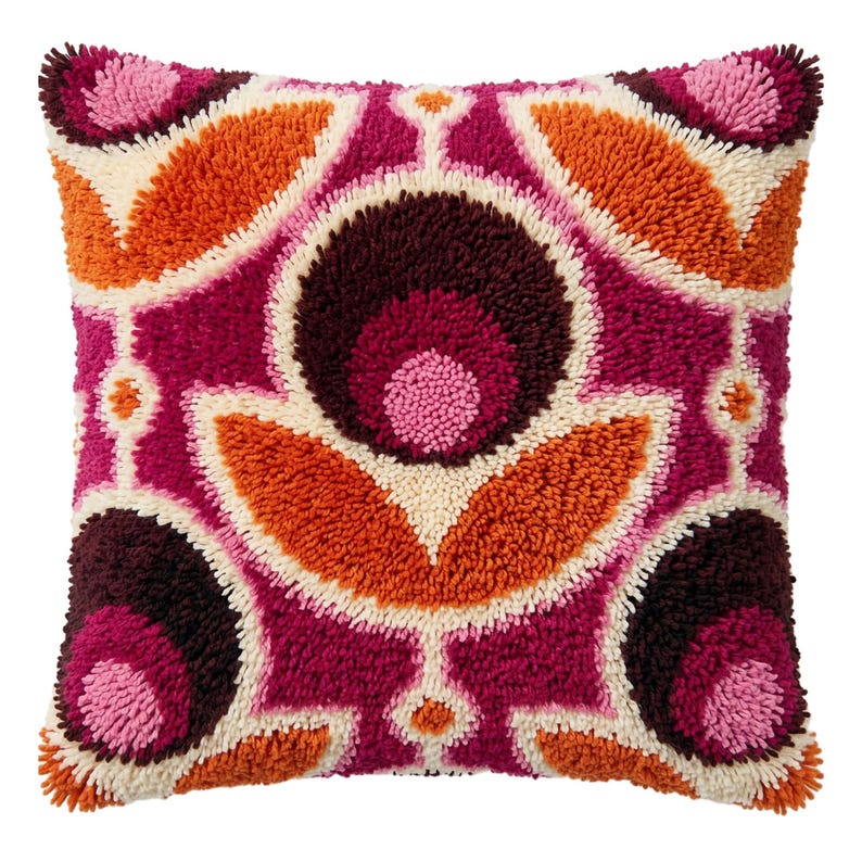 May include: A square throw pillow featuring a textured, tufted surface with a symmetrical floral-inspired pattern. The design incorporates vibrant shades of magenta, deep burgundy, bright orange, and cream in a repeating geometric arrangement.