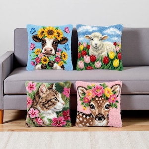 May include: Four decorative throw pillows with animal designs. The pillows feature a cow with sunflowers, a lamb in a field of tulips, a cat surrounded by pink flowers, and a deer with a floral crown. The pillows are square and have a textured appearance.