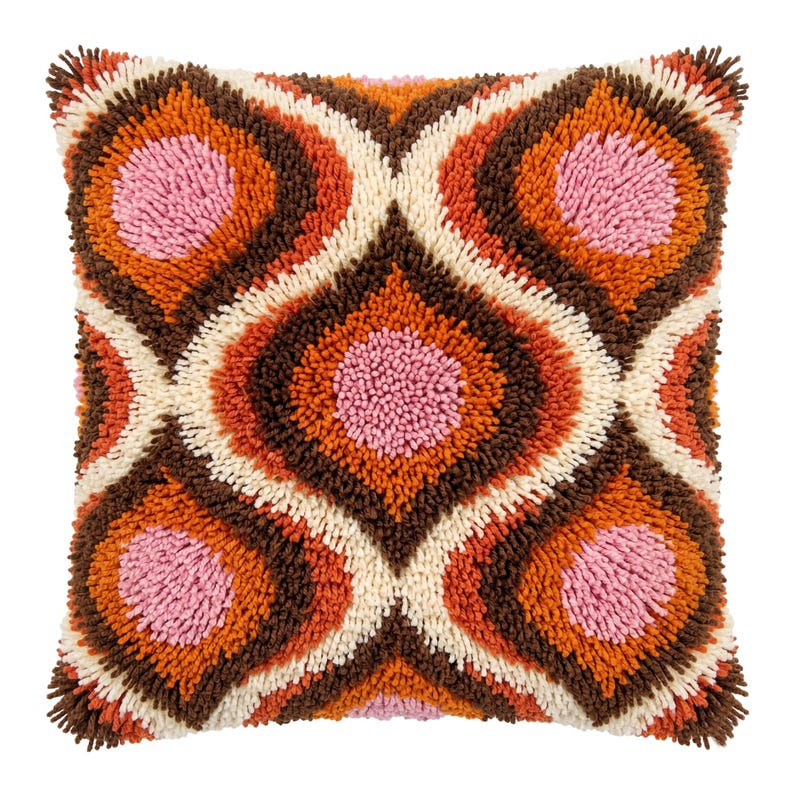 May include: A square throw pillow featuring a shaggy, tufted texture with a repeating geometric pattern. The design consists of concentric diamond shapes in shades of pink, orange, dark brown, and cream, creating a dense, multi-layered surface.
