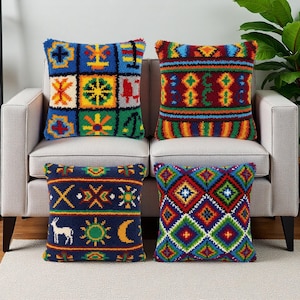 May include: Four decorative throw pillows with colorful geometric and folk art designs. The pillows feature a variety of patterns, including squares, diamonds, and stylized symbols, in shades of blue, red, green, yellow, and white. The pillows are placed on a neutral-toned sofa.