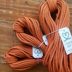 May include: Three spools of orange cotton cord, each tied in a loop. The cord is labeled "The Mountain Thread Co. Solid Braid Made in USA."