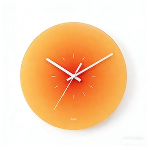 May include: A round orange wall clock with white hands and minimalist hour markers. The clock face has a gradient effect, transitioning from a lighter orange in the center to a darker shade at the edges. The brand name "hans" is printed at the bottom.
