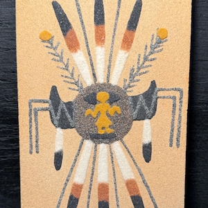 May include: A white ceramic mug with a black handle and the text "But First, Coffee" in a bold, black font. The mug is set against a blurred background, suggesting a cozy setting.