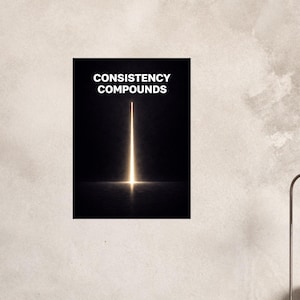 May include: A poster with the words "CONSISTENCY COMPOUNDS" in white text at the top. A bright, vertical light beam shines from the bottom center, reflecting on the dark surface below. The background is black.