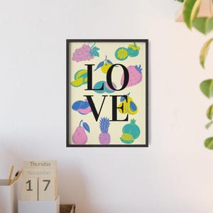 Könnte beinhalten: Ein gerahmter Kunstdruck mit dem Wort "LOVE" in schwarzen Großbuchstaben. Das "O" ist eine Erdbeere, und die Buchstaben sind von farbenfrohen Illustrationen von Früchten wie Trauben, Ananas und Birnen umgeben. Der Hintergrund ist hellbeige.