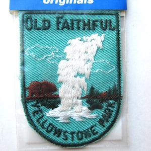May include: A rectangular embroidered patch with rounded bottom corners featuring a teal background. The text OLD FAITHFUL is at the top and YELLOWSTONE PARK is at the bottom. A white geyser erupts in the center with a brown bear to the left.