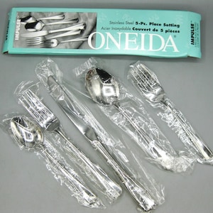 May include: A five-piece stainless steel flatware set by Oneida, including a dinner fork, salad fork, dinner knife, soup spoon, and teaspoon. Each piece is individually wrapped in clear plastic and presented with its original teal box.