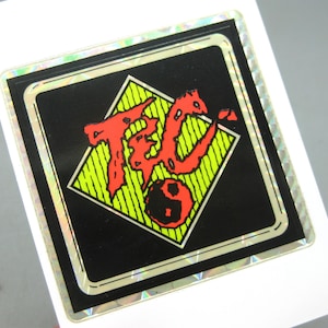 Puede incluir: Una taza de cer&aacute;mica blanca con un asa negra y el texto "But First, Coffee" en negro, con una fuente de estilo manuscrito. La taza est&aacute; sobre una superficie blanca.