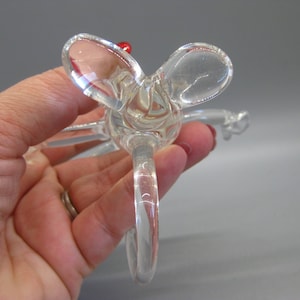 May include: Clear glass bottle stopper with a decorative butterfly design. The stopper features a loop handle and a small red accent. The butterfly wings are rounded and transparent.