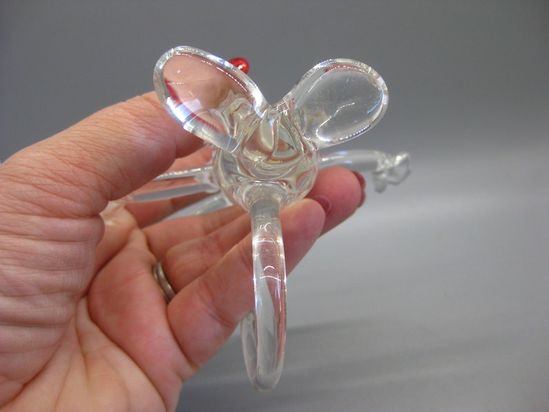 May include: Clear glass bottle stopper with a decorative butterfly design. The stopper features a loop handle and a small red accent. The butterfly wings are rounded and transparent.