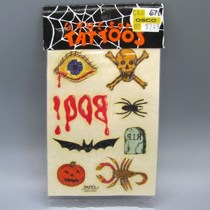 May include: A package of Halloween temporary tattoos with images of a bloody eye, skull and crossbones, spider, bat, pumpkin, scorpion, and the word "BOO!" with dripping blood.