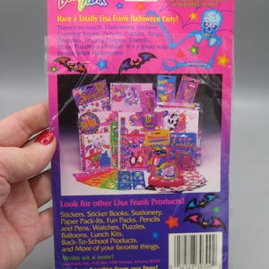 Puede incluir: Un paquete de pegatinas de Lisa Frank con tem&aacute;tica de Halloween, con un fondo rosa y morado. El paquete presenta una ilustraci&oacute;n de esqueleto, murci&eacute;lagos y varias pegatinas. El texto incluye "&iexcl;4 hojas con 77 pegatinas en total!"