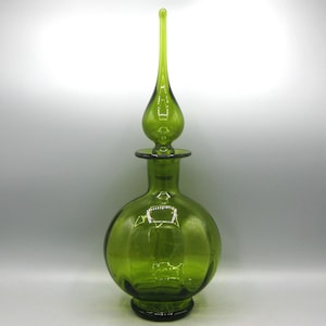 Könnte beinhalten: Eine grüne dekorative Glasflasche mit rundem Körper und langem, spitzem Verschluss. Die Flasche hat eine bauchige Form mit dunkelgrünem Boden und passendem Verschluss. Das Glas ist transparent.