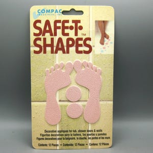 May include: A package of Compac Industries Safe-T-Shapes decorative appliques for tubs, shower doors, and walls. The packaging features two pink foot-shaped appliques and two pink circular appliques, with a total of 12 pieces included in the set.