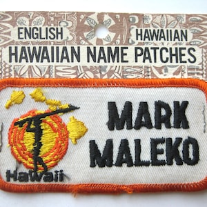 May include: Embroidered name patch with the name "MARK MALEKO" in black block letters. The patch features a Hawaiian design with a figure holding a pole, a yellow and orange sun, and the word "Hawaii". The patch has an orange border.