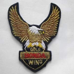 May include: Embroidered patch featuring a golden eagle with outstretched wings. The eagle has a white head and yellow beak, with the words "GOLD HONDA WING" embroidered below. The patch is outlined in black.