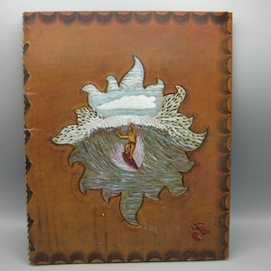 Peut inclure: Livre vintage relié en cuir marron avec une illustration de scène de surf. L'œuvre représente un surfeur chevauchant une vague, avec un soleil et des nuages stylisés au-dessus. La couverture a une bordure décorative et une empreinte de patte.