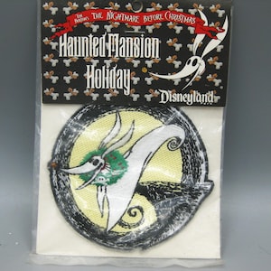 May include: A Haunted Mansion Holiday Disneyland patch featuring Zero from The Nightmare Before Christmas. The patch has a circular design with a yellow background and a black border. The top of the patch has the text "The Nightmare Before Christmas".