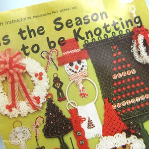May include: A vintage craft instruction book titled "'Tis the Season to be Knotting." The cover features various handmade Christmas ornaments, including a wreath, snowman, and Christmas tree, all in red, white, and black.