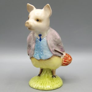 May include: A ceramic figurine of a pig wearing a light purple jacket, blue vest, and yellow pants. The pig is standing on a green grassy base and has a small red and orange basket. The figurine has a whimsical, storybook aesthetic.