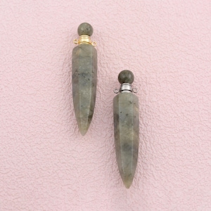 May include: Two elongated, pointed pendants made of mottled grey stone. One pendant features a gold-toned metal cap with a small loop at the top, while the other pendant has a silver-toned metal cap with a matching loop for attachment.